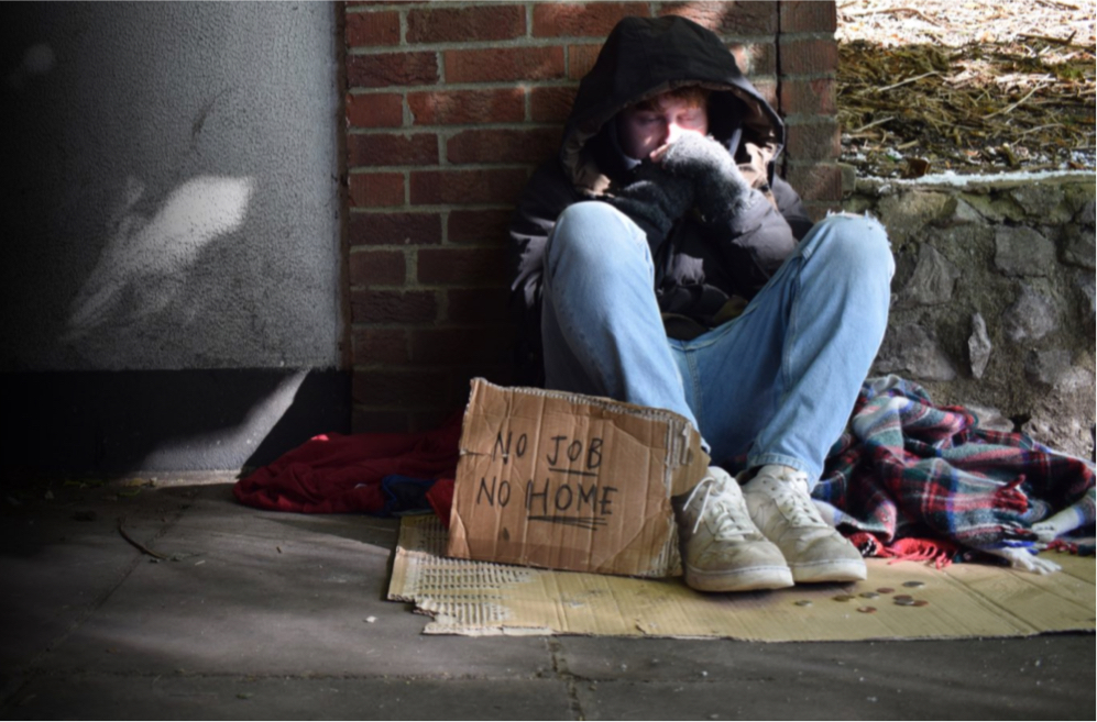Homeless man sat on the street pavement